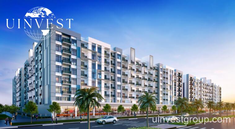 Exterior rendering of Lawnz by Danube Properties in Dubai International City, showing four eight-storey, country-themed freehold apartment buildings with pastel facades, geometric motifs, private balconies, surrounded by landscaped gardens, a community swimming pool, outdoor sports courts, and palm trees under a bright blue sky.