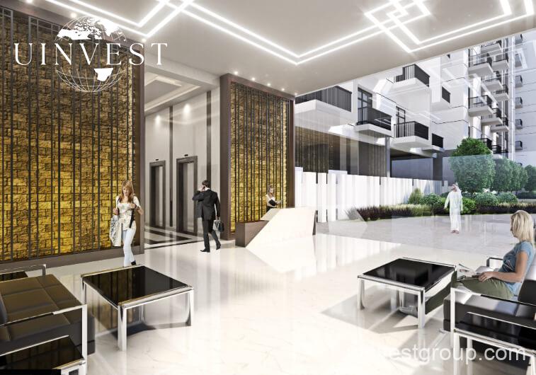 Exterior rendering of Lawnz by Danube Properties in Dubai International City, showing four eight-storey, country-themed freehold apartment buildings with pastel facades, geometric motifs, private balconies, surrounded by landscaped gardens, a community swimming pool, outdoor sports courts, and palm trees under a bright blue sky.