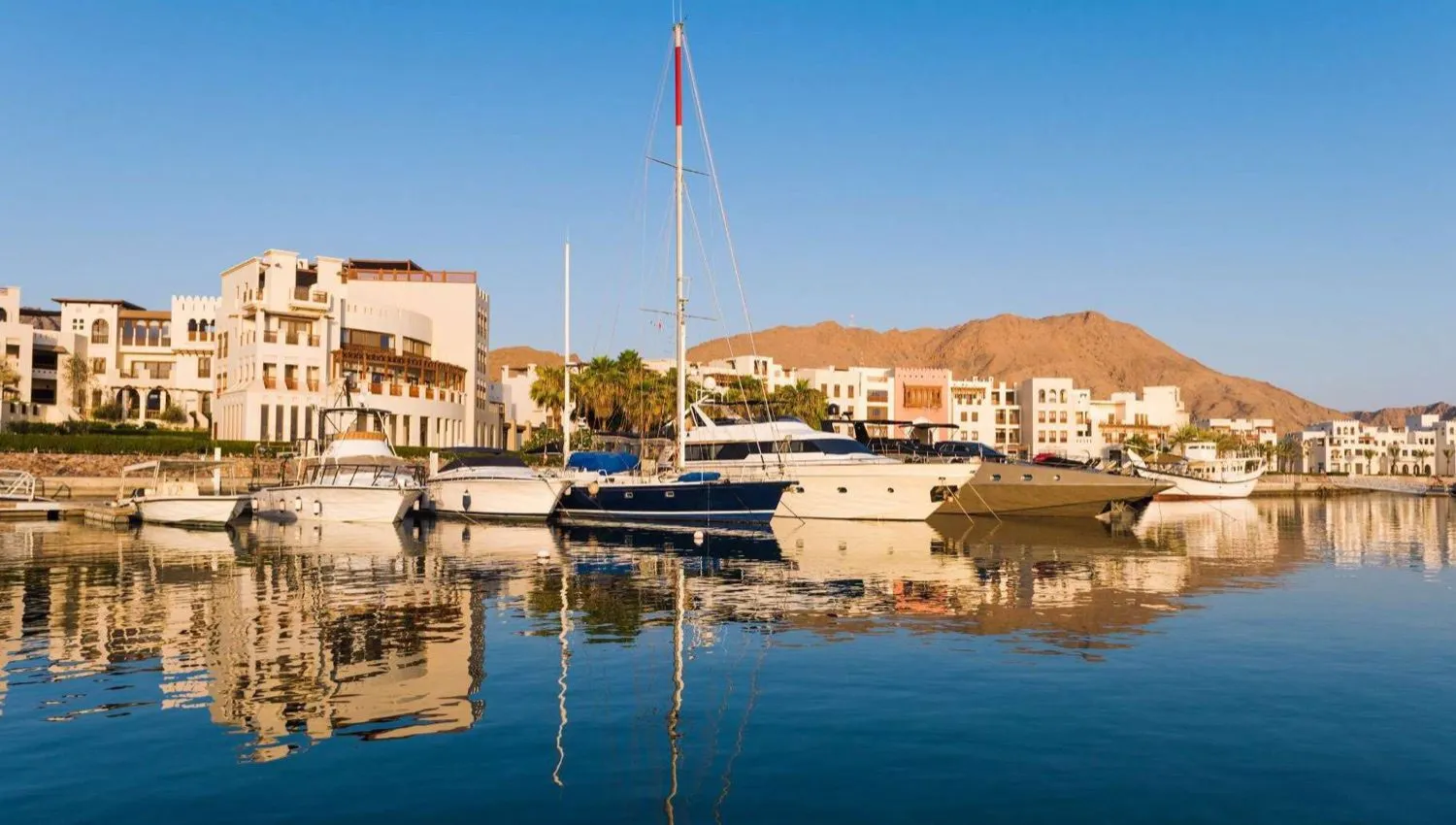 Yachts berthed at Jebel Sifah Marina, Oman, with Al Hajar mountains behind