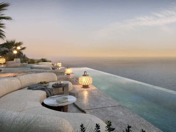 Clifftop infinity pool and lounge terrace at AIDA at sunset over the Gulf of Oman.