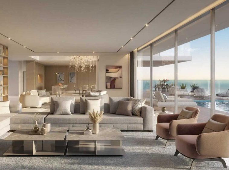 Living room in an AIDA villa in a beige palette, opening to the pool terrace and the Gulf of Oman.