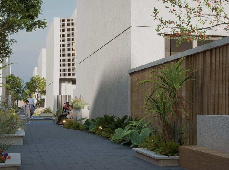 Landscaped shaded walkway between villas at Al Ahlam District, with perforated decorative screens on the facades.