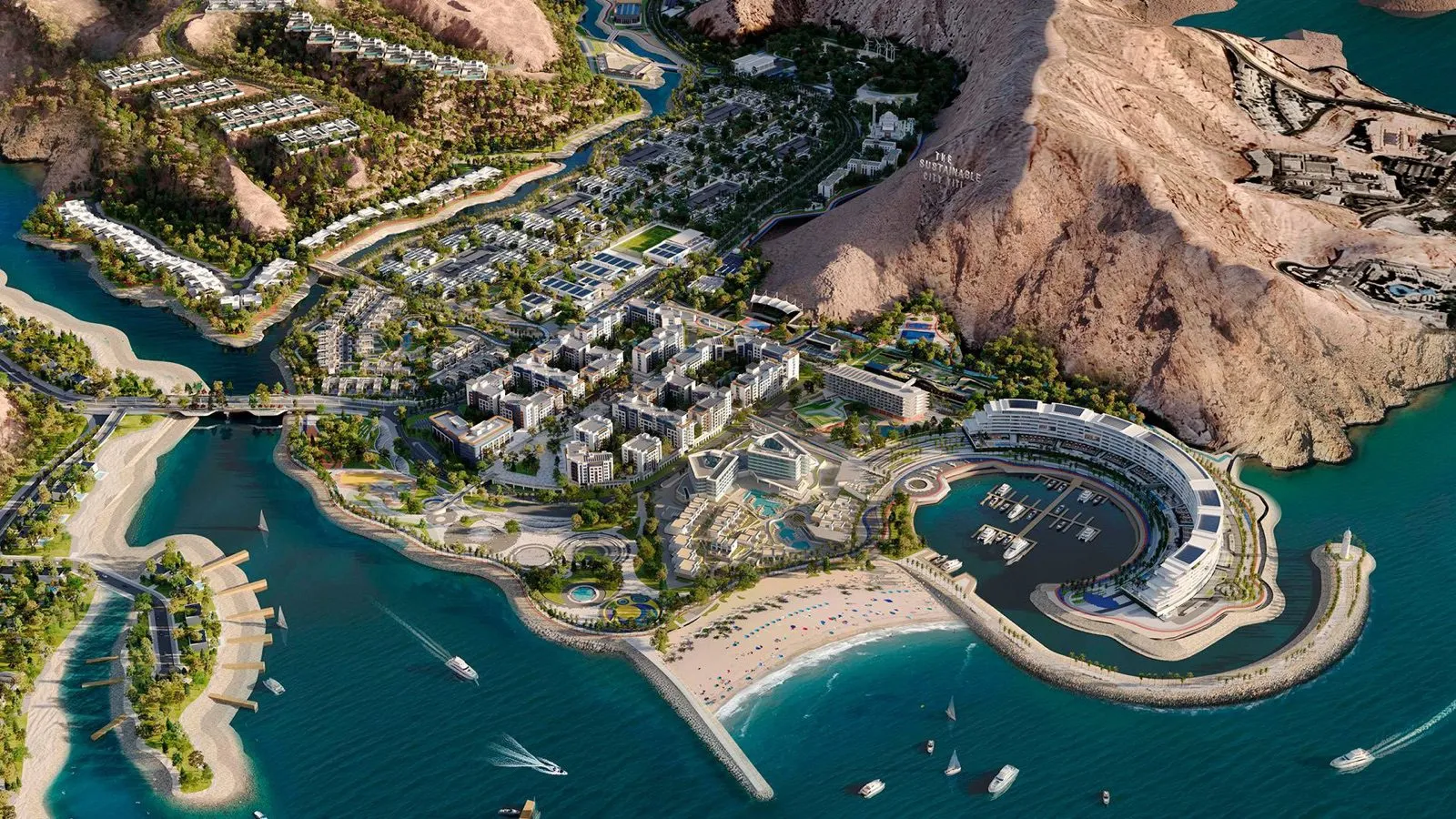 Aerial view of The Sustainable City Yiti on the Gulf of Oman coast, showing the marina, beach, The Arc Residences and the surrounding mountains.