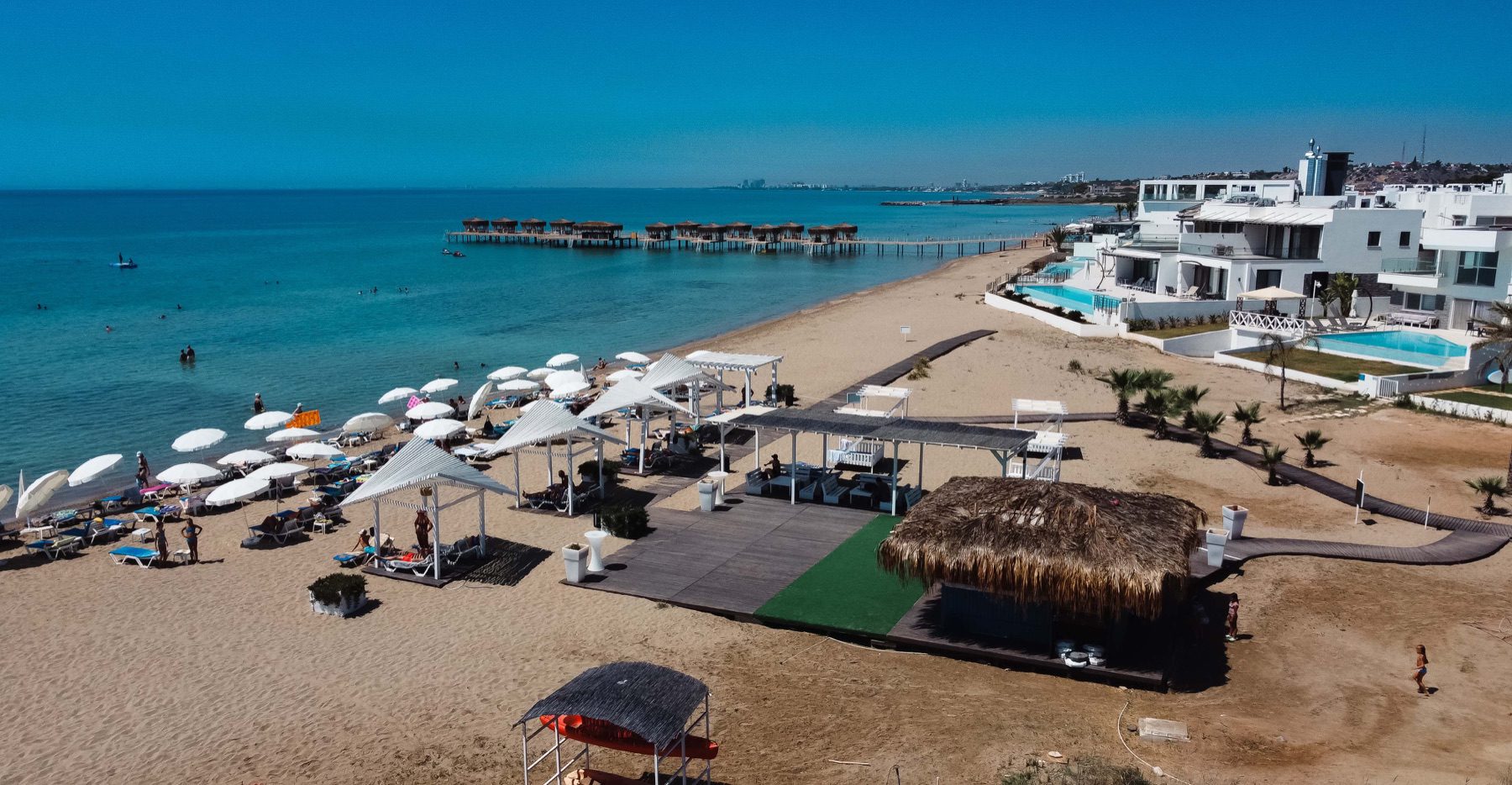 Caesar Beach sandy shore with sunshades, bar and villas