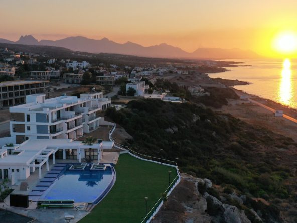 Aerial view of Caesar Cliff villas and pool above the sea at sunset