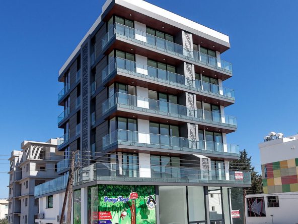 Photo of an apartment building with glazed balconies and a shop at street level