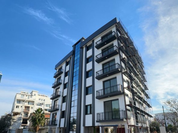Photo of a multi-storey apartment building with dark balcony frames, from a low angle