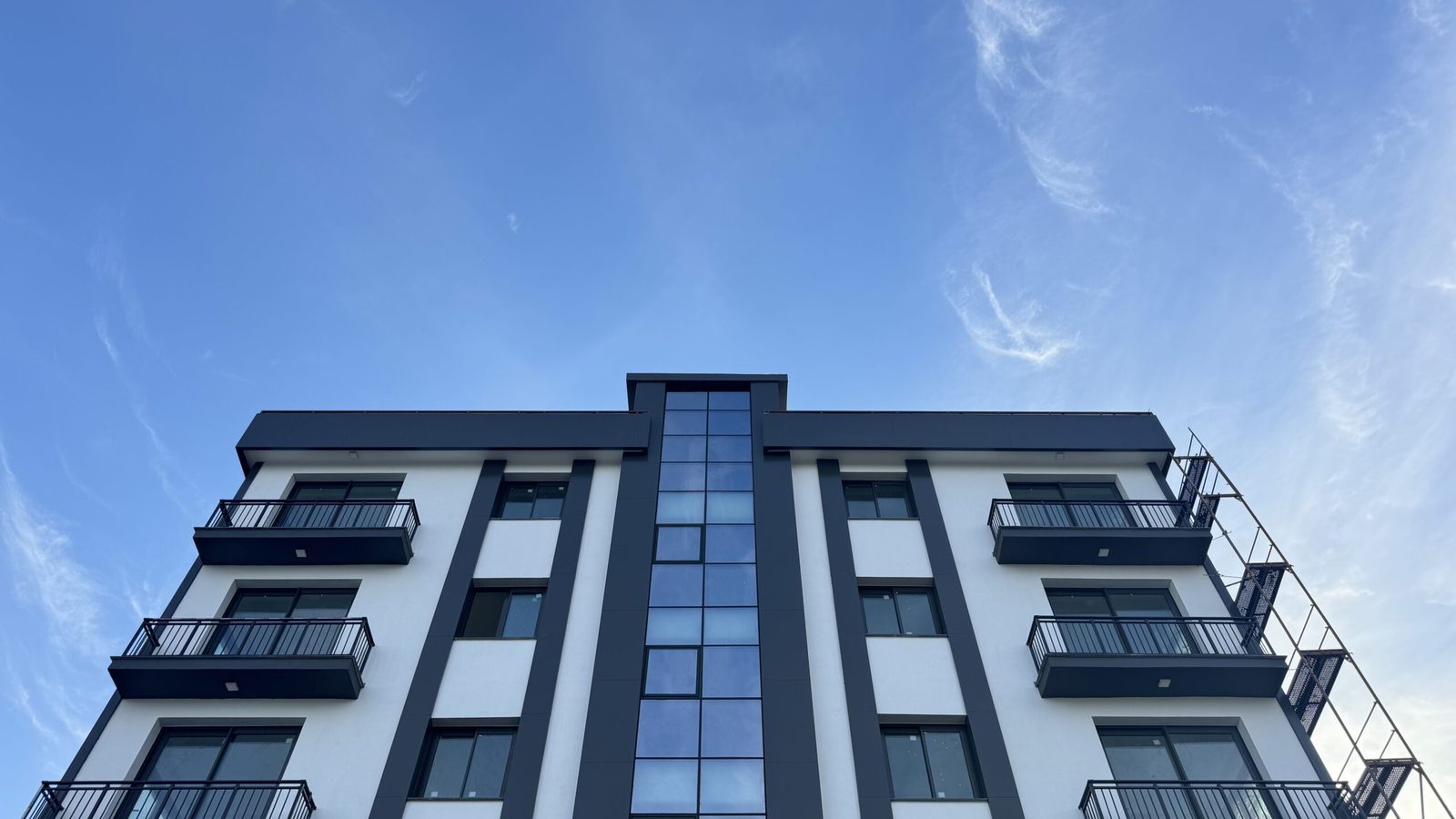 Low-angle photo of the facade and glazed stair column against a blue sky