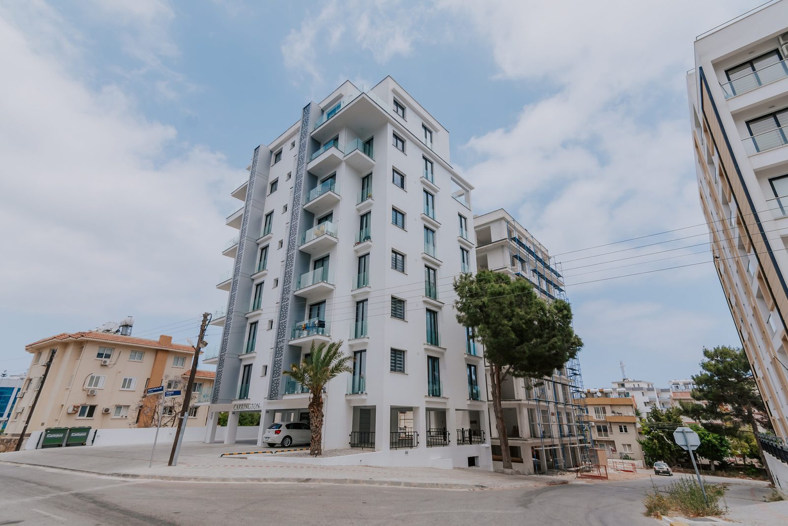Photo of a completed white apartment tower seen from the street corner