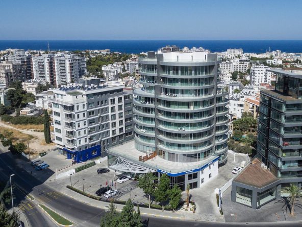 Aerial photo of the curved glazed tower and neighbouring buildings with the sea behind