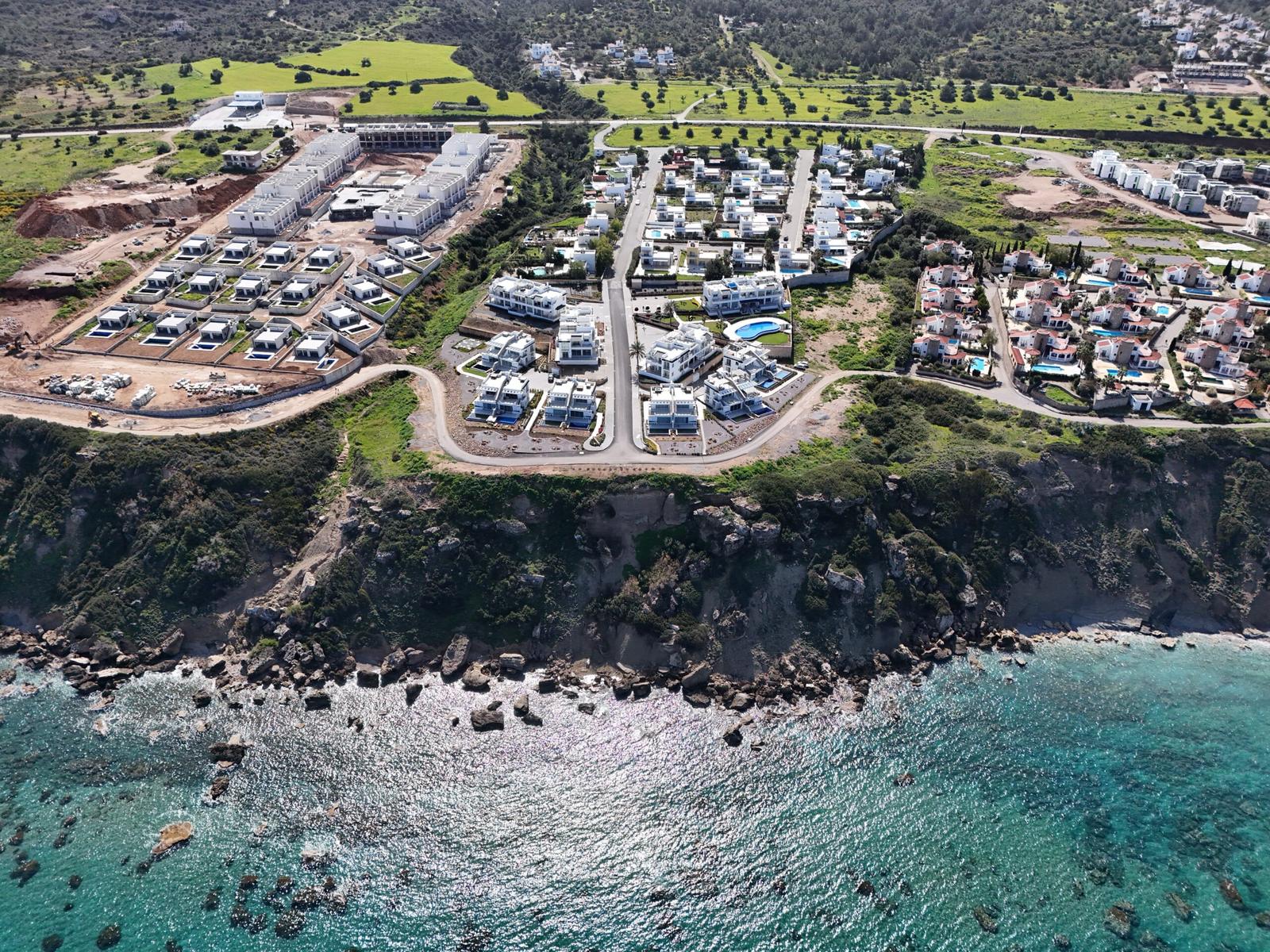 Aerial photo of a housing estate on a cliff above a turquoise bay