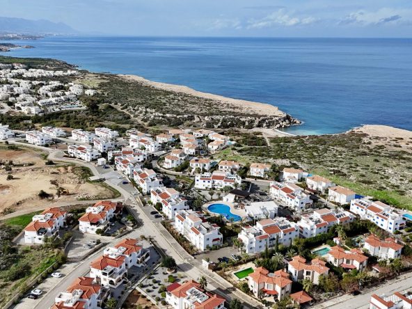 Aerial photo of white low-rise housing near a long sandy coastline