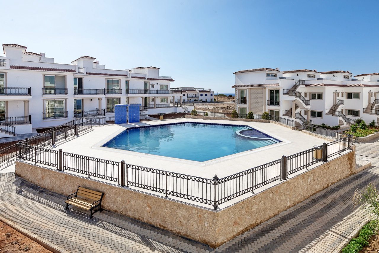 Communal swimming pool with railing in front of white apartment blocks