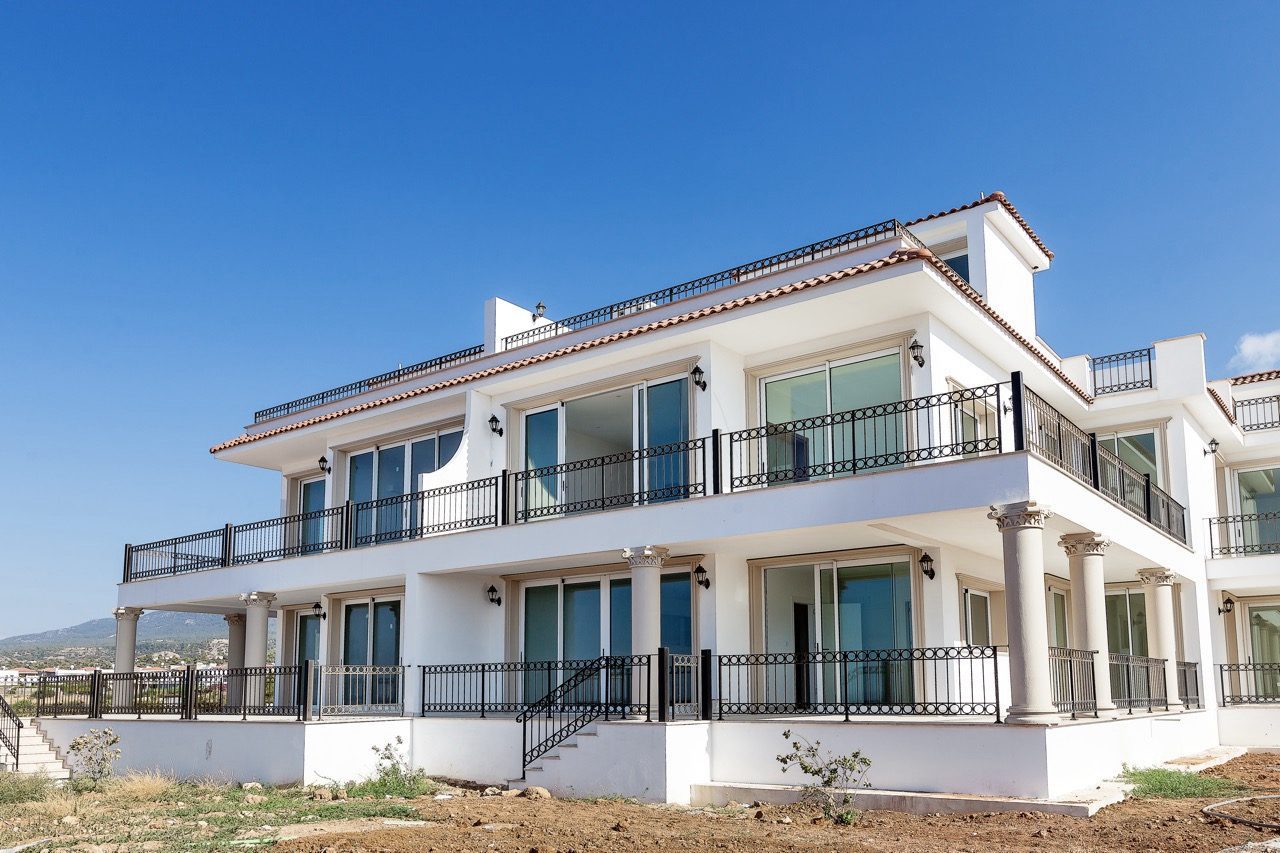 White two-storey apartment block with balconies and terrace