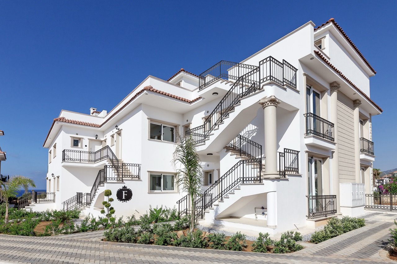 White apartment block with external staircase and landscaped entrance