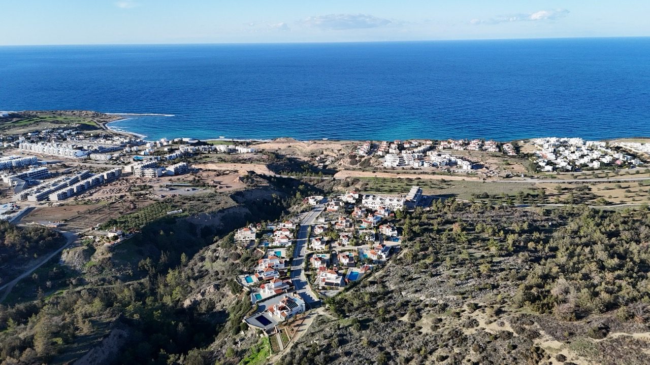 Aerial view of the villa estate on the hillside with the coast and sea beyond