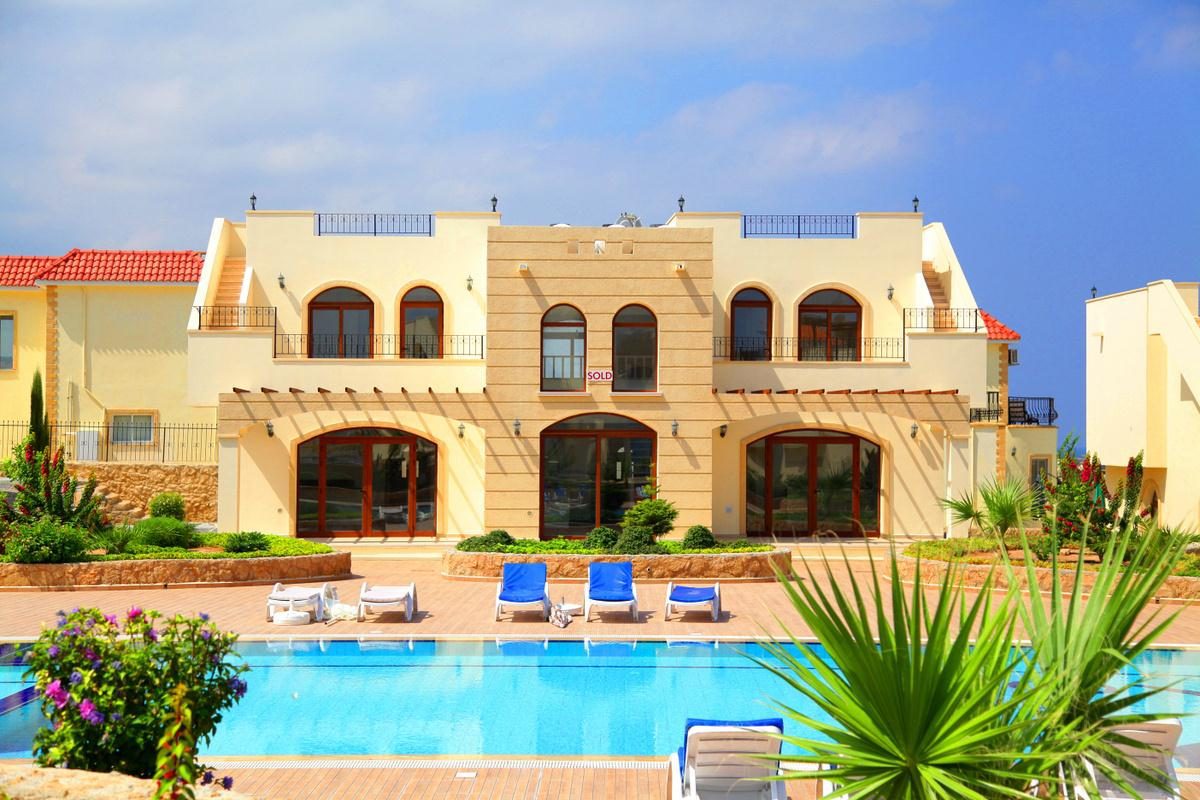 Stone-trimmed loft apartment block with arched windows above the pool terrace