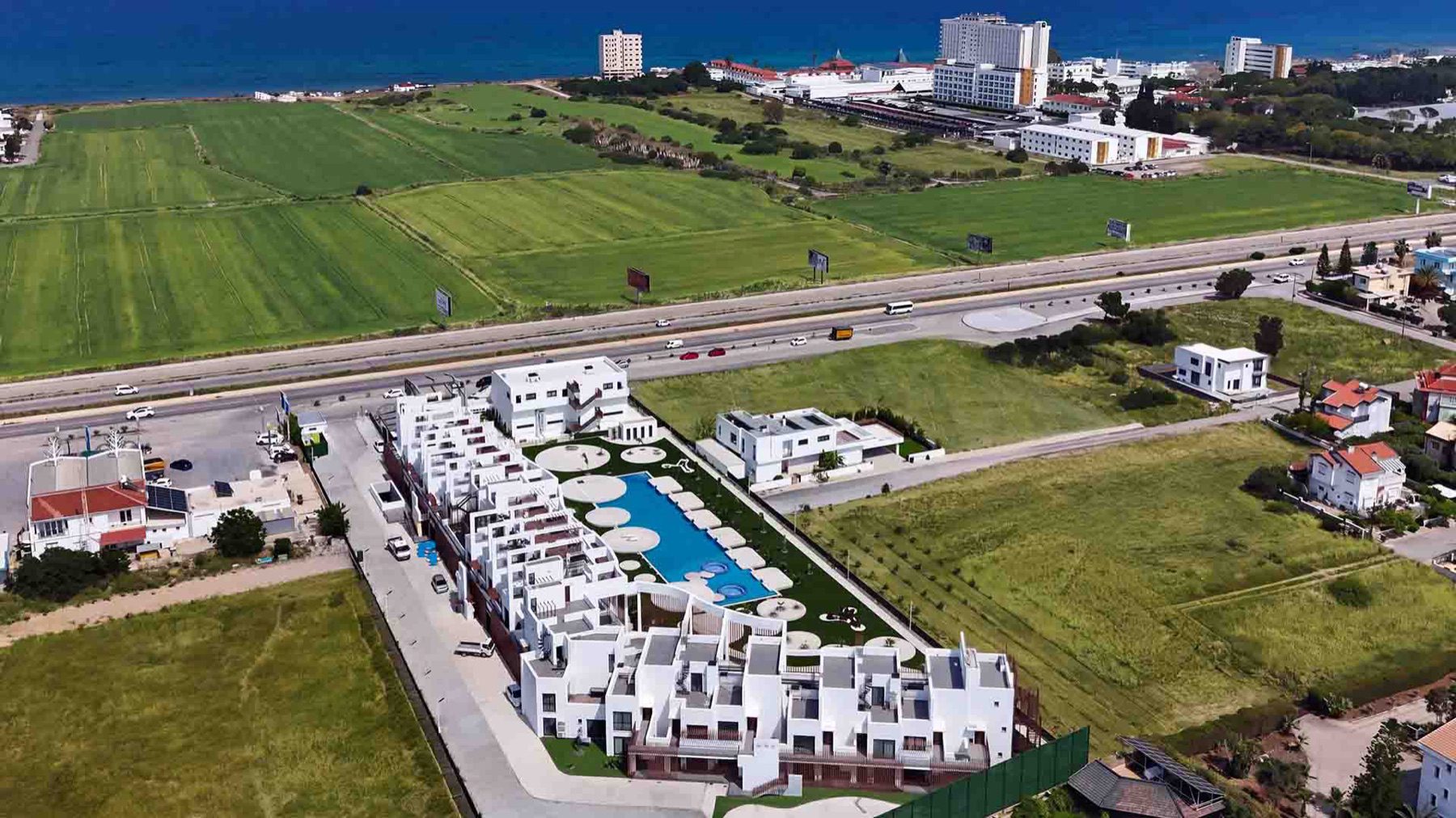aerial view of Neo Residence blocks around a long swimming pool with the sea beyond