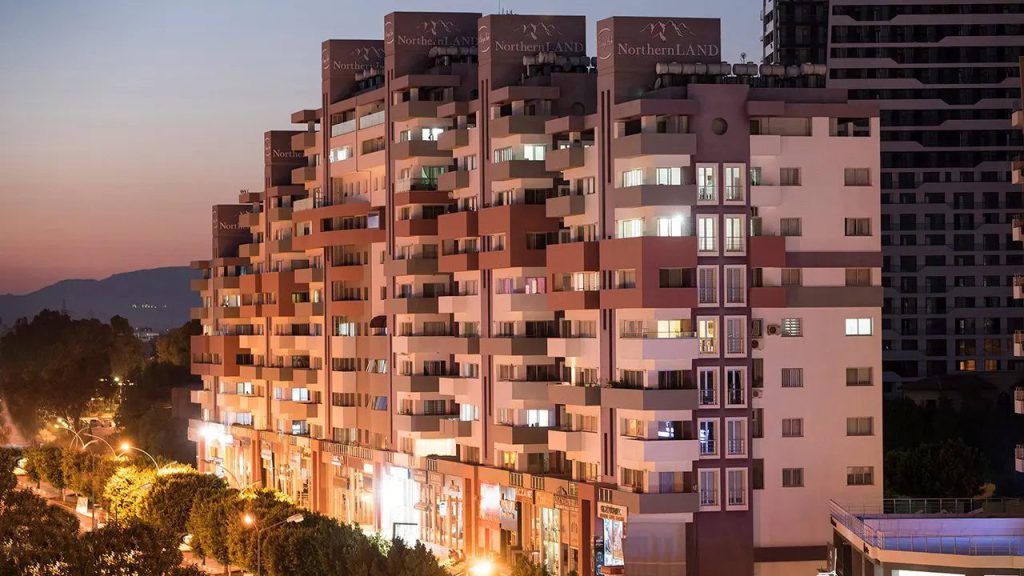 Alasya Park Famagusta terraced apartment block at dusk with lit windows