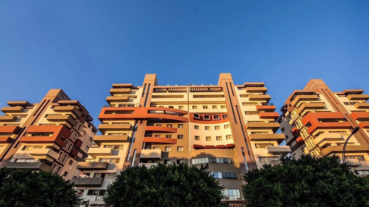 Upward view of three terraced apartment blocks against a blue sky