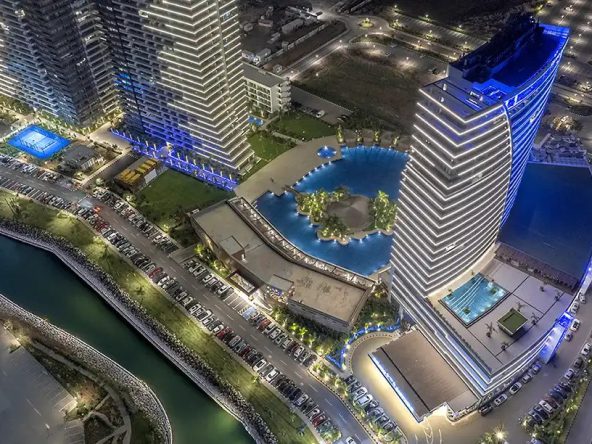 Aerial night view of the hotel tower, pool and canal