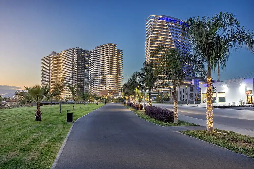 Dusk photograph of residential towers beyond a landscaped road