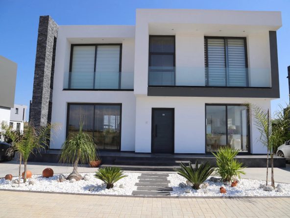 Photograph of a two-storey white villa with a front garden