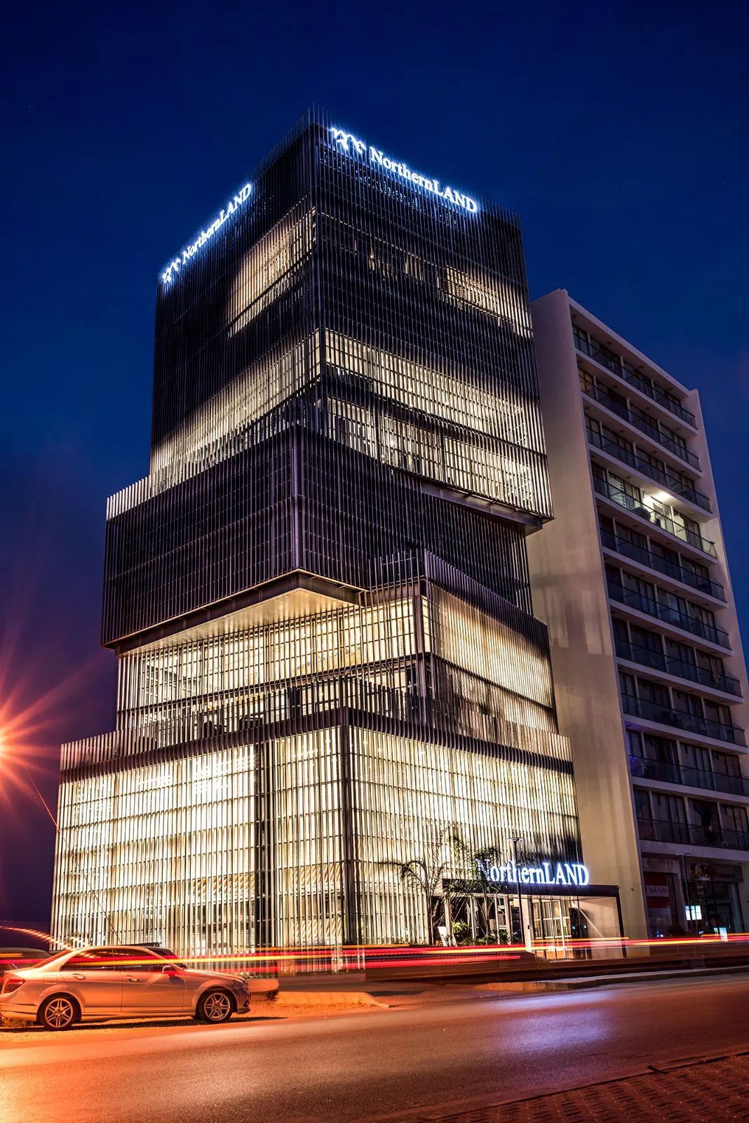 Glass tower lit at dusk beside a street