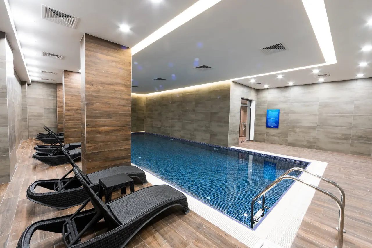 Indoor swimming pool with sun loungers and wood-clad walls