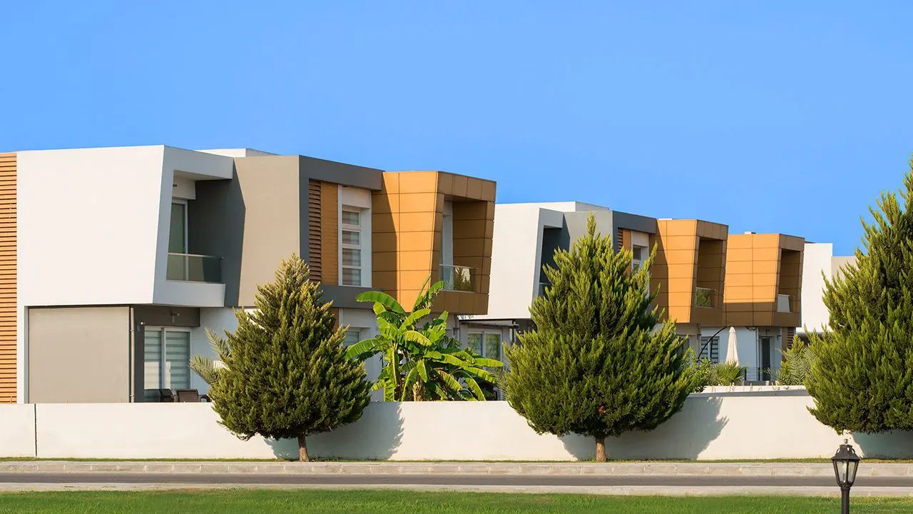 Row of modern Sakli Kent villas with orange panel details and garden trees