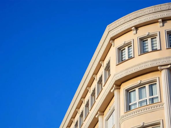 Curved cream facade of the building with arched windows against blue sky