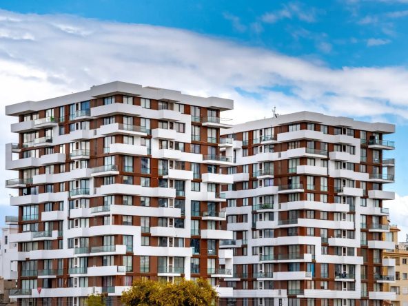 Two white and brown terraced residential towers seen from the street