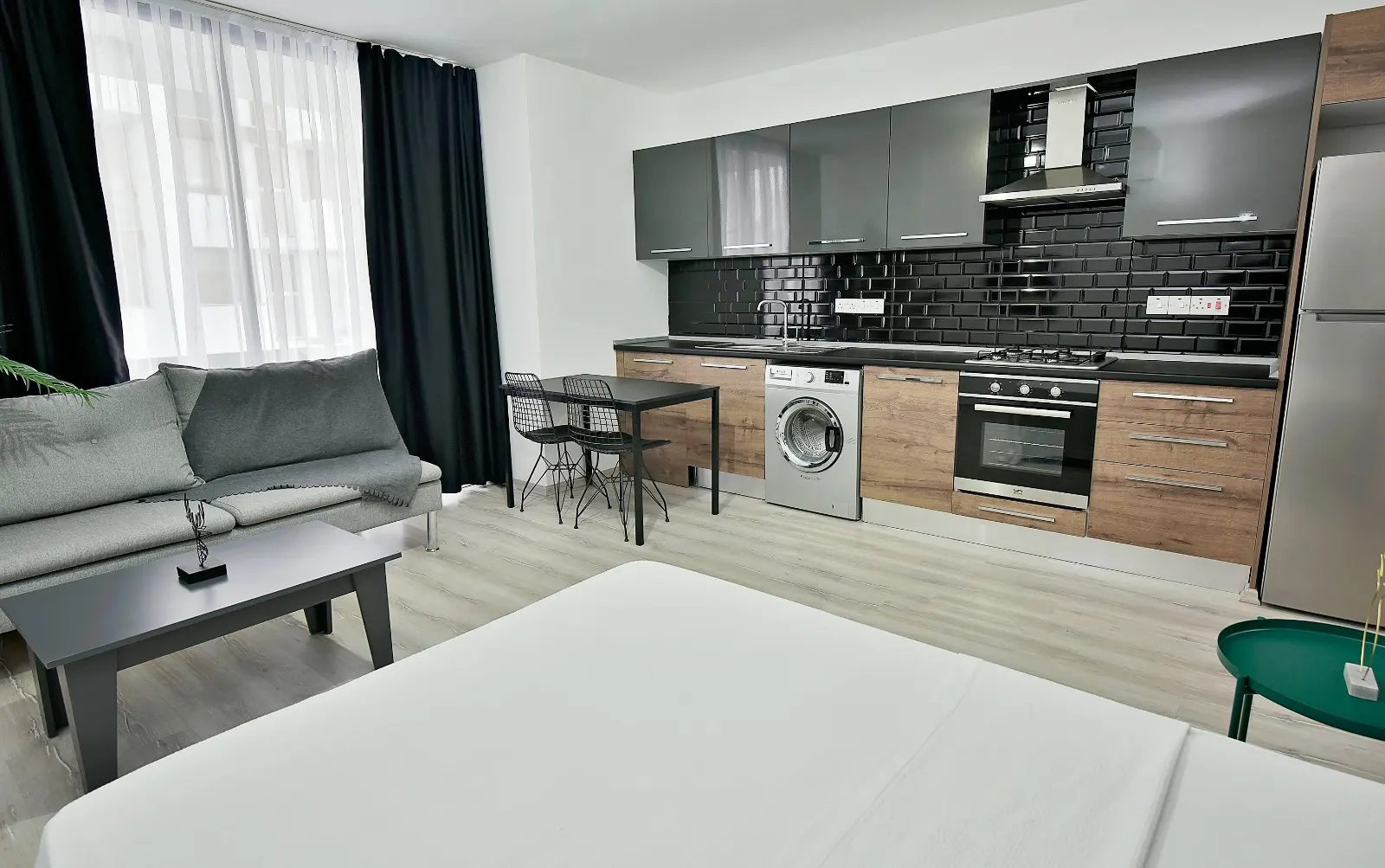 Open-plan studio with sofa, dining table, kitchen and double bed